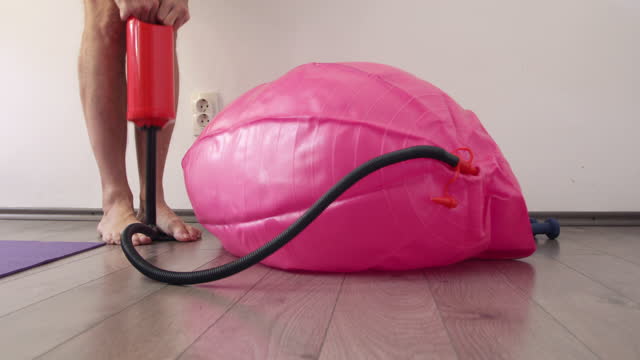 Man inflating fitness ball using hand pump