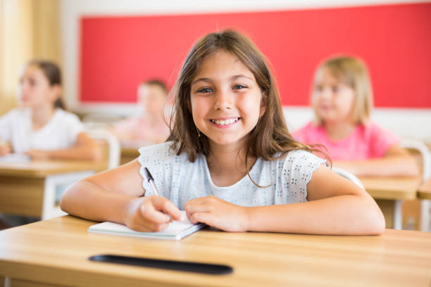 istock Smiling diligent tween schoolgirl studying with classmates 1489129075
