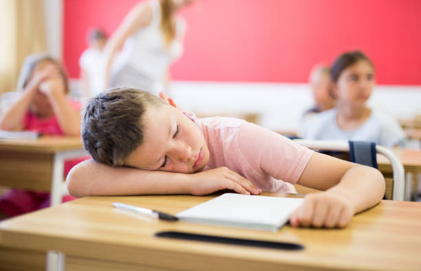 istock Tired school boy sleeping in classroom during lesson 1489129100