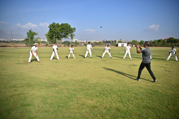 Cricket coach working with a group of team players on their throwing and catching  technique