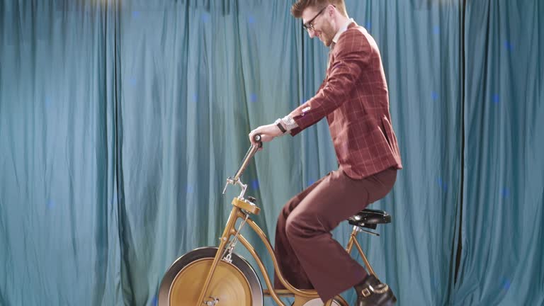 Retro Man Riding Vintage Exercise Bike in Broadcast Setting