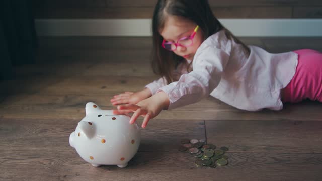 A beautiful 4s girl counts coins and puts them in a piggy bank. Save money, pocket money, be frugal