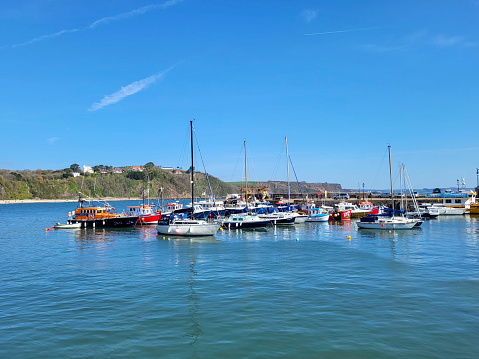 Yachts moored in the historic fishing village of Tenby on a sunny blue sky summers day at high tide.