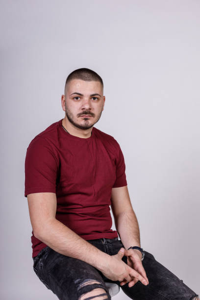 istock Charming young man sitting against white background, smiling with confidence 1489135562
