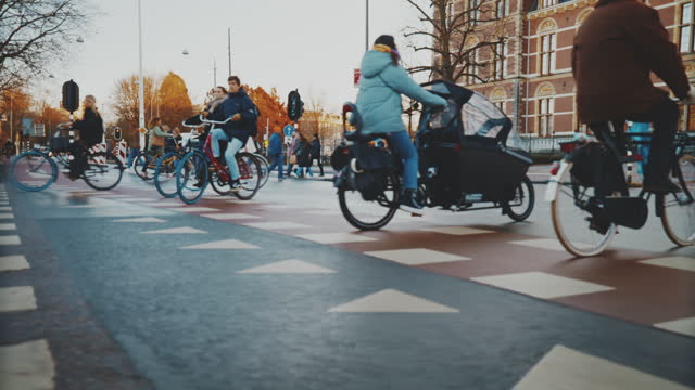 Commuters cycling on street and people walking on sidewalk