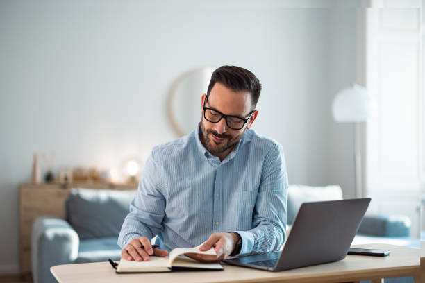 istock Confident man reading notes from the notebook, sitting at the home office. 1489136424