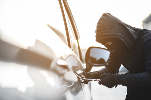 Close up car thief hand holding screwdriver tamper yank and glove black stealing automobile trying door handle to see if vehicle is unlocked  trying to break into inside. stock photo