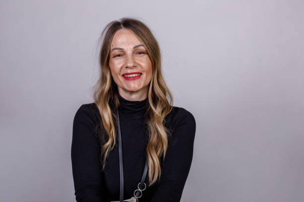 istock Charming mature woman sitting against white background, smiling confidently at camera 1489136837