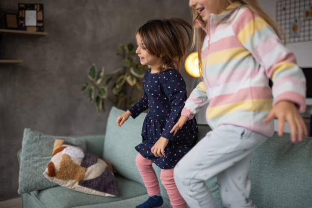 istock Two little girls playing and jumping on a sofa at home 1489138027
