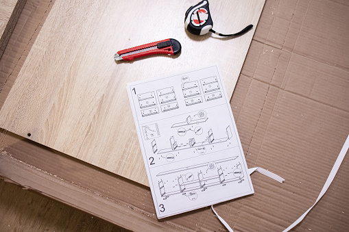 Flat lay, top view, mockup, copy space. Paper instructions for assembling furniture, schematic drawing, construction knife, home assemle work, tape measure. Repair, renovation. Working instructions