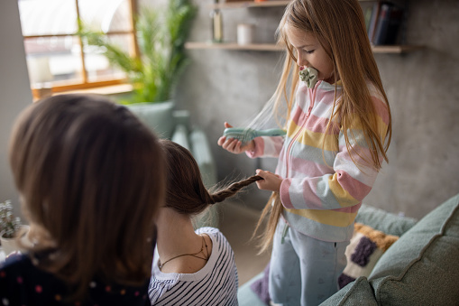 Daughters braiding their mother's hair at home