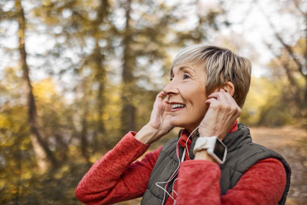 istock Senior woman putting headphones on 1489141663