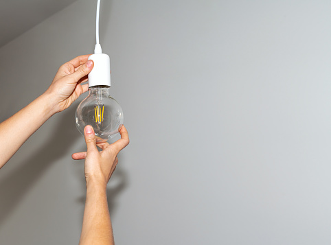 Light bulb and hands close-up, replacing bulb, energy saving, reduction electricity consumption.