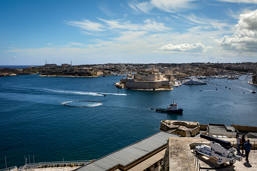 Valletta, Malta - April 18, 2023: View from the Upper Barakka Gardens to Grand Harbour. Sea landscape, fishing ship with a trawl netting entering the port.