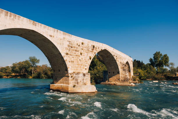 istock Flowing river beneath the historic Aspendos bridge, surrounded by lush vegetation and the timeless beauty of this ancient landmark. 1489143920