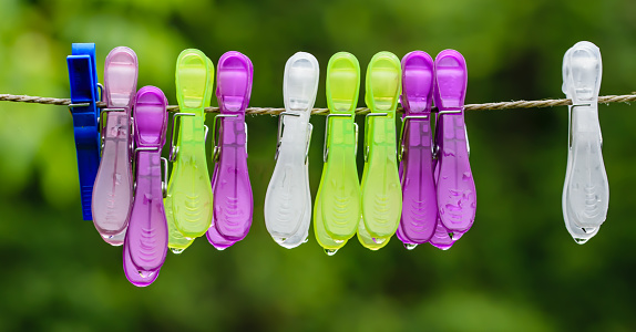 Wallpaper of colorful clothespins hanging on a clothesline with water droplets after rain in macro close-up