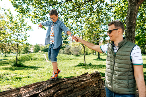 Father and son playing at the park near lake at the day time. Concept of friendly family.Father and son playing at the park on bench at the day time. Concept of friendly family.