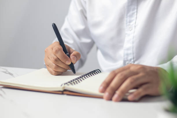 istock Male hand writing a note in a notebook concept of business people working 1489149678