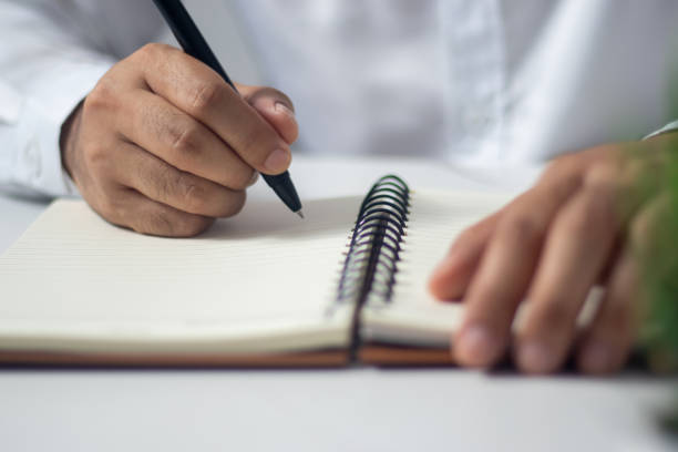 istock Male hand writing a note in a notebook concept of business people working 1489149766