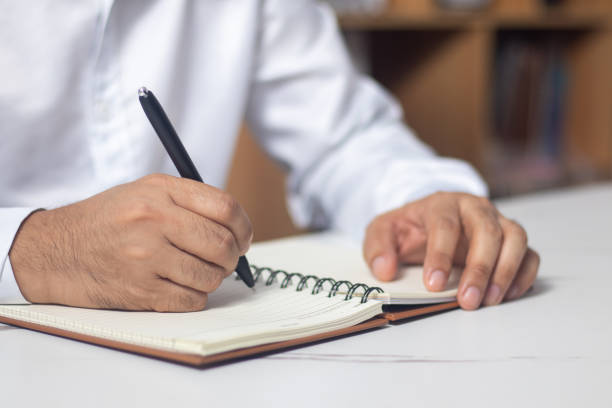 istock Male hand writing a note in a notebook concept of business people working 1489149784