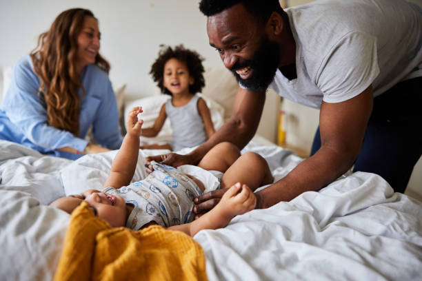 istock Dad and mom playing with their cute little sons on their bed 1489152527