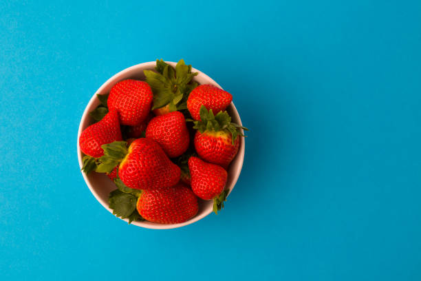istock Fresh strawberries and green leaf in bowl isolated on blue background, 1489155933