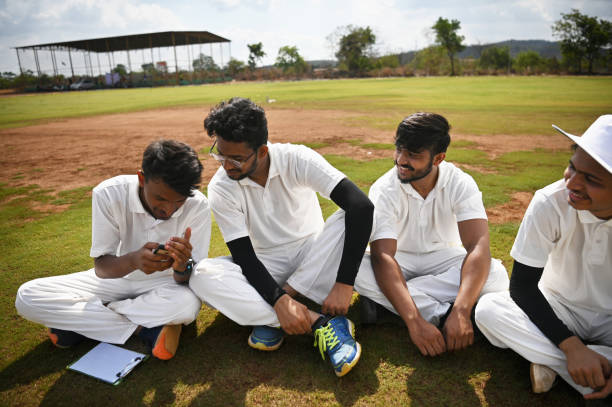 istock Team members checking their mobile phone while relaxing on the ground after cricket match 1489165653