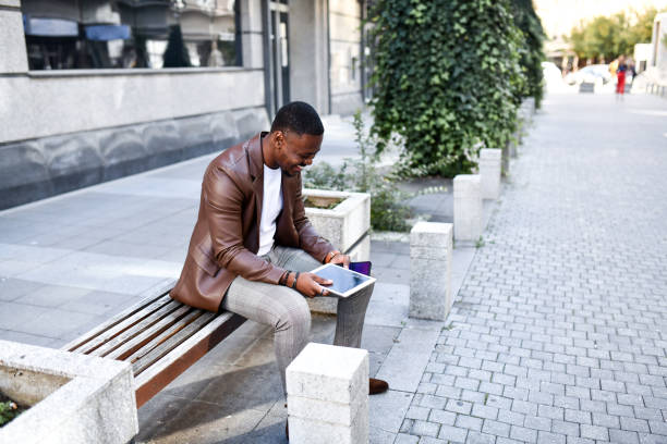 istock Elegant African Businessman Laughing While Watching Funny Video On Digital Tablet Outside 1489166831