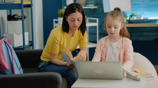 istock Mother and daughter reading book together and doing homework 1489168941