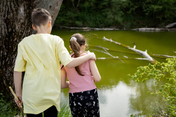 istock Brother and sister standing near river 1489171616