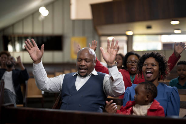 istock Congregation with eyes closed and arms raised praying in church 1489173276