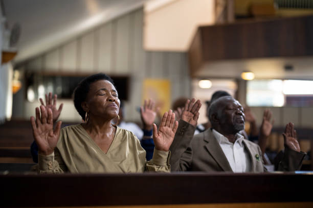 istock Senior woman with eyes closed and hands raised in prayer 1489173301