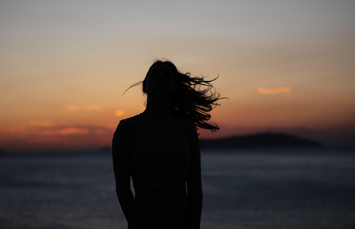 Silhouette of young woman at sunset.