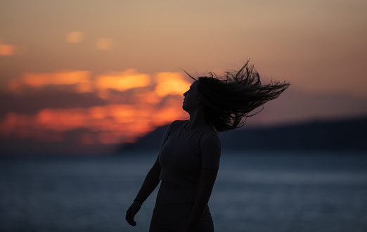 Silhouette of young woman at sunset.