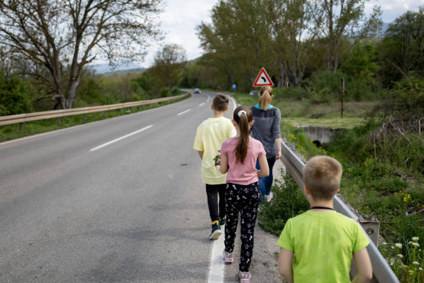 Mother and three kids walking in line down the road. Enjoying family time together after a nice walk.