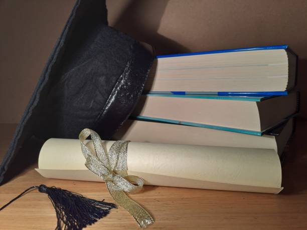 istock Graduation hat with degree paper on a stack of books 1489176835