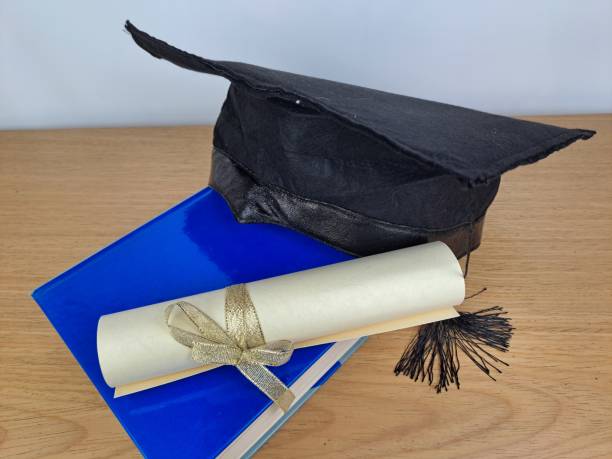 istock Graduation hat with degree paper on a stack of books. Copy space 1489176939