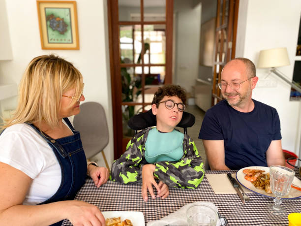 Family with disabled son sitting at table ready to eat