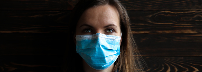 Woman in medical mask on wooden background. Time of quarantine. Coronavirus pandemia. Virus danger infection. Cold or flu illnesses.