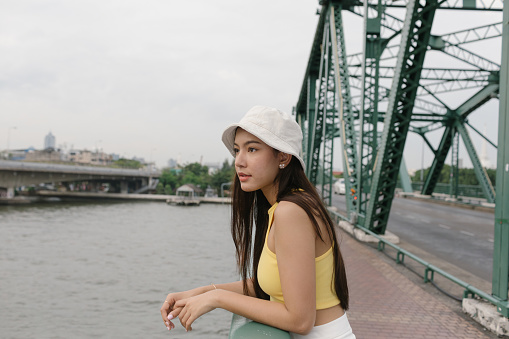 Girl posing on bridge looking over the water