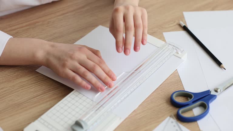 Hand cutting white sheet of paper with paper cutter