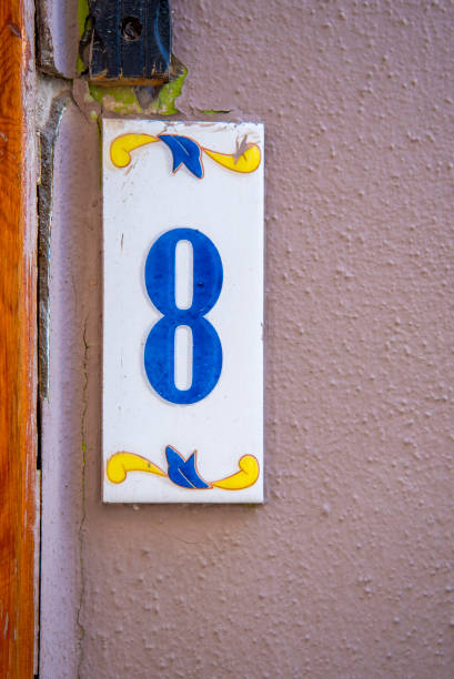 A sign with the number 8 in blue on a pink wall. A sign with the number 8 in blue on a pink wall. The concept of architecture and construction. ceramic tile house numbers stock pictures, royalty-free photos & images