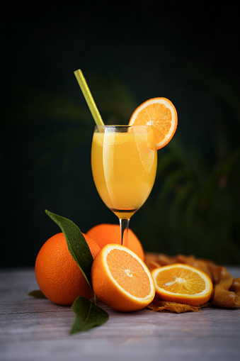 Front view view of orange fruit and glass of orange juice on white background.