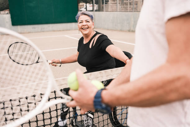 mujer latina discapacitada practica tenis en silla de ruedas con entrenador - wheelchair tennis physical impairment athlete fotografías e imágenes de stock
