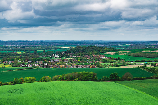 Dramatic aerial view of gently rolling patchwork farmland with pretty wooded boundaries, in the beautiful surroundings of the Cotswolds, England, UK. Stitched panoramic image.