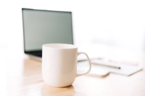 istock White mug without inscriptions in front of a laptop and a notepad on a wooden table 1489189357