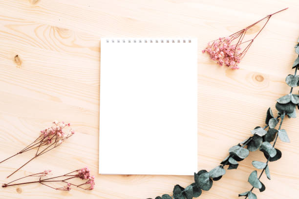 istock Empty white notepad with dried flowers on wooden table 1489189375
