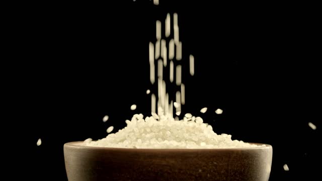 Japanese rice falls in slow motion. Close-up of raw rice grain in a bowl