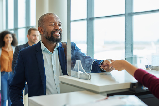 Ticket, glass window and black man in airport or hotel line for passport check for travel service. Happy customer person at security booth or counter for business booking and buying pass at seller
