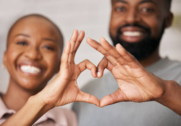 istock Love, hands in heart and black couple with smile for relationship, dating and commitment in home. Happy, emoji and face of black woman and man smile with hand shape for bonding, romance and trust 1489192307